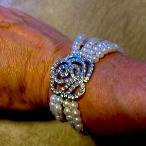 Four layered beaded pearl bracelet with a silver flower charm